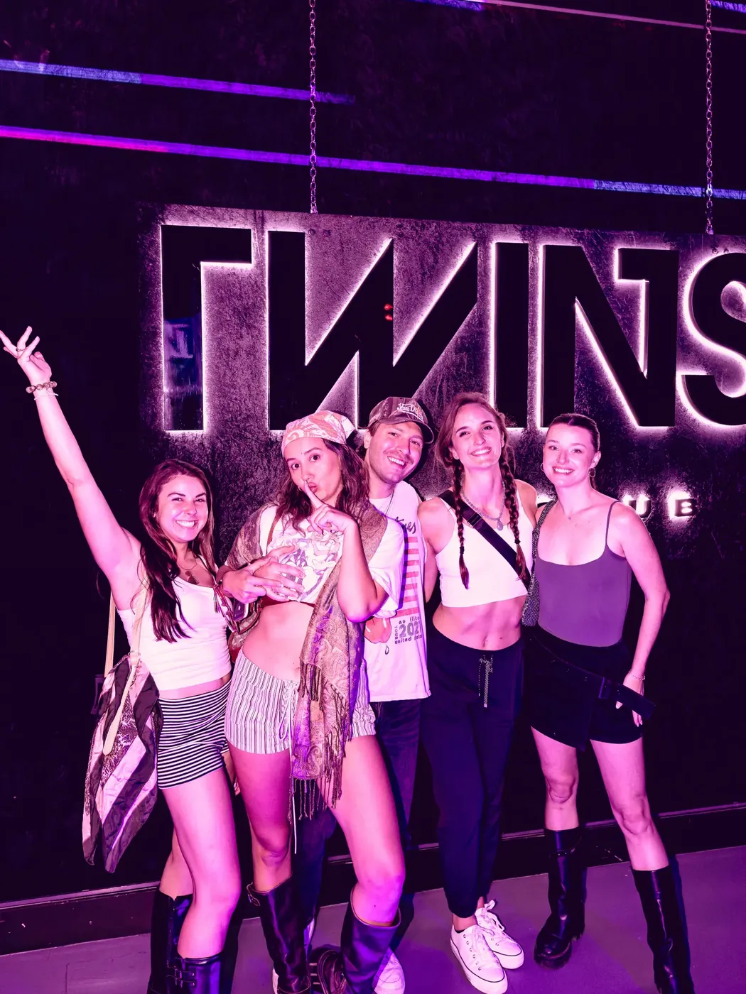 Friends posing at the TWINS logo wall